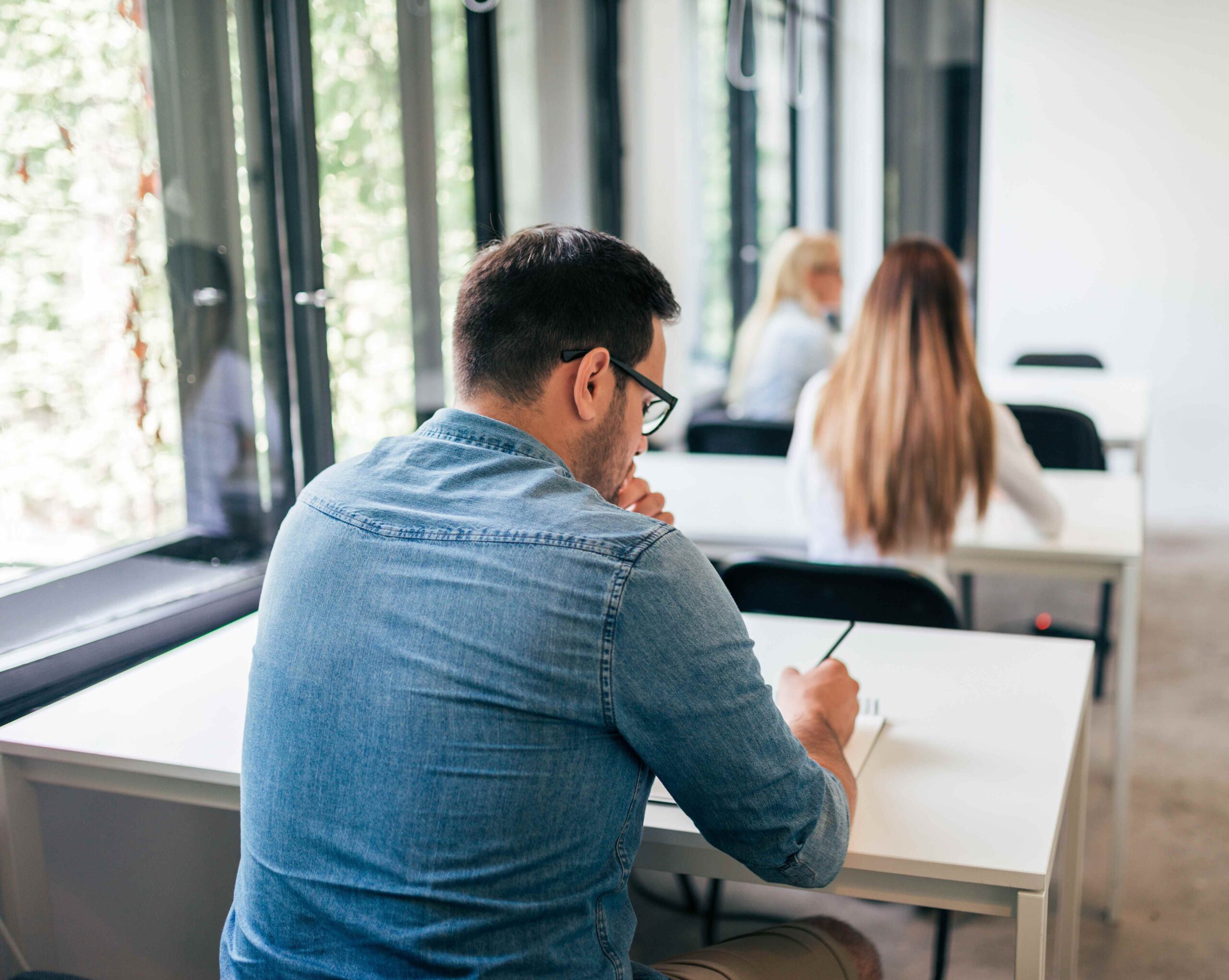 Two professionals engaged in an online video conference on a laptop in an indoor setting.